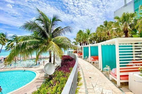 Picturesque pool area at The Diplomat Resort with cabanas, palm trees, and ocean views under blue skies