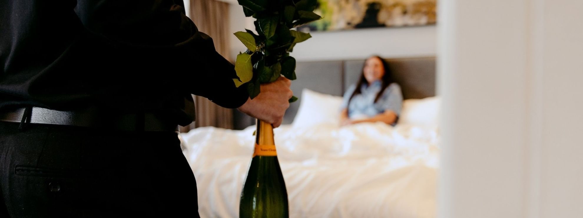 Person delivering flowers and champagne to a hotel room for the Romantic Escape Package.