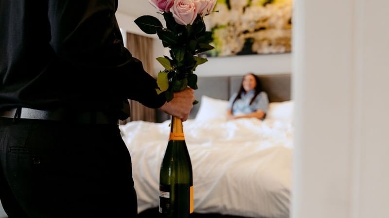 Person delivering flowers and champagne to a hotel room for the Romantic Escape Package.