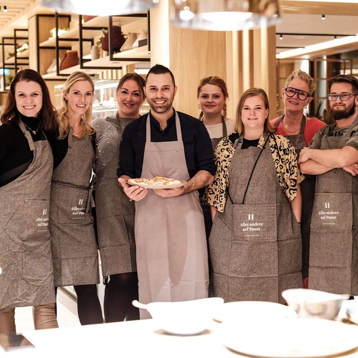 Group of smiling waitstaff in aprons standing in a restaurant at Falkensteiner Hotel Belgrade