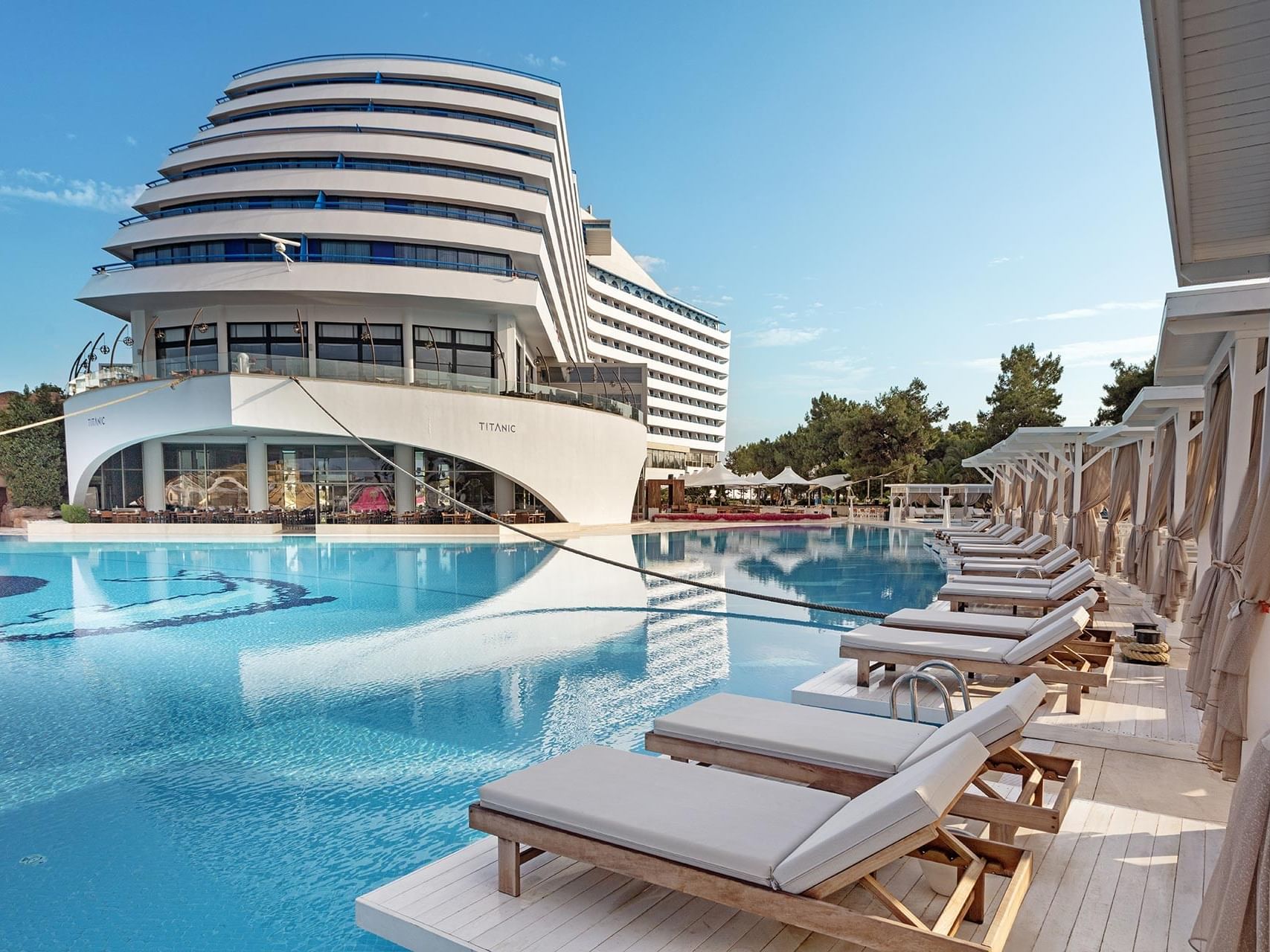 Sun loungers arranged by the outdoor pool at Titanic Deluxe Lara on a sunny day