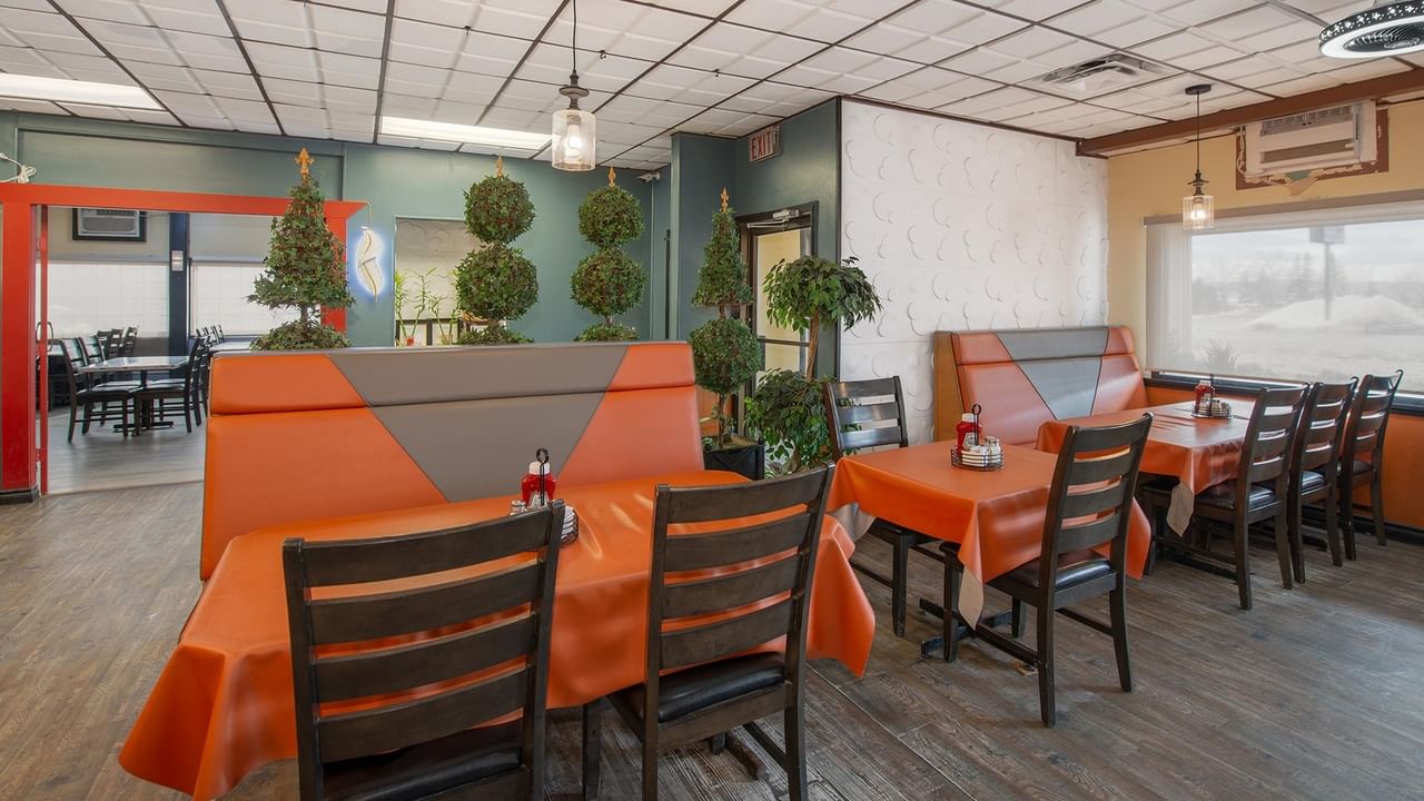 Tables and chairs in the restaurant with orange tablecloths.