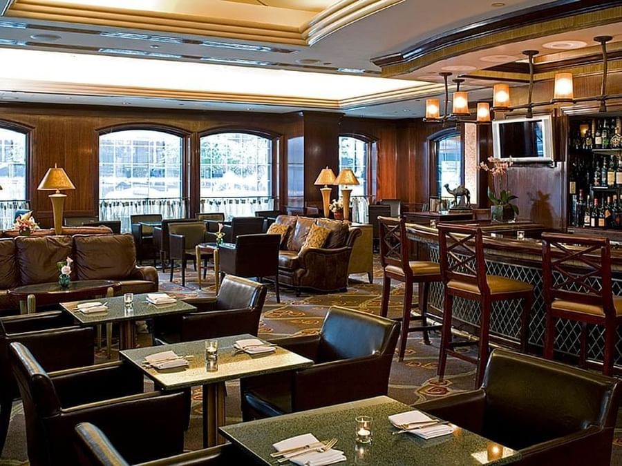 Elegant hotel lounge with wood paneling, arched windows, leather seating, and a bar area at Warwick New York