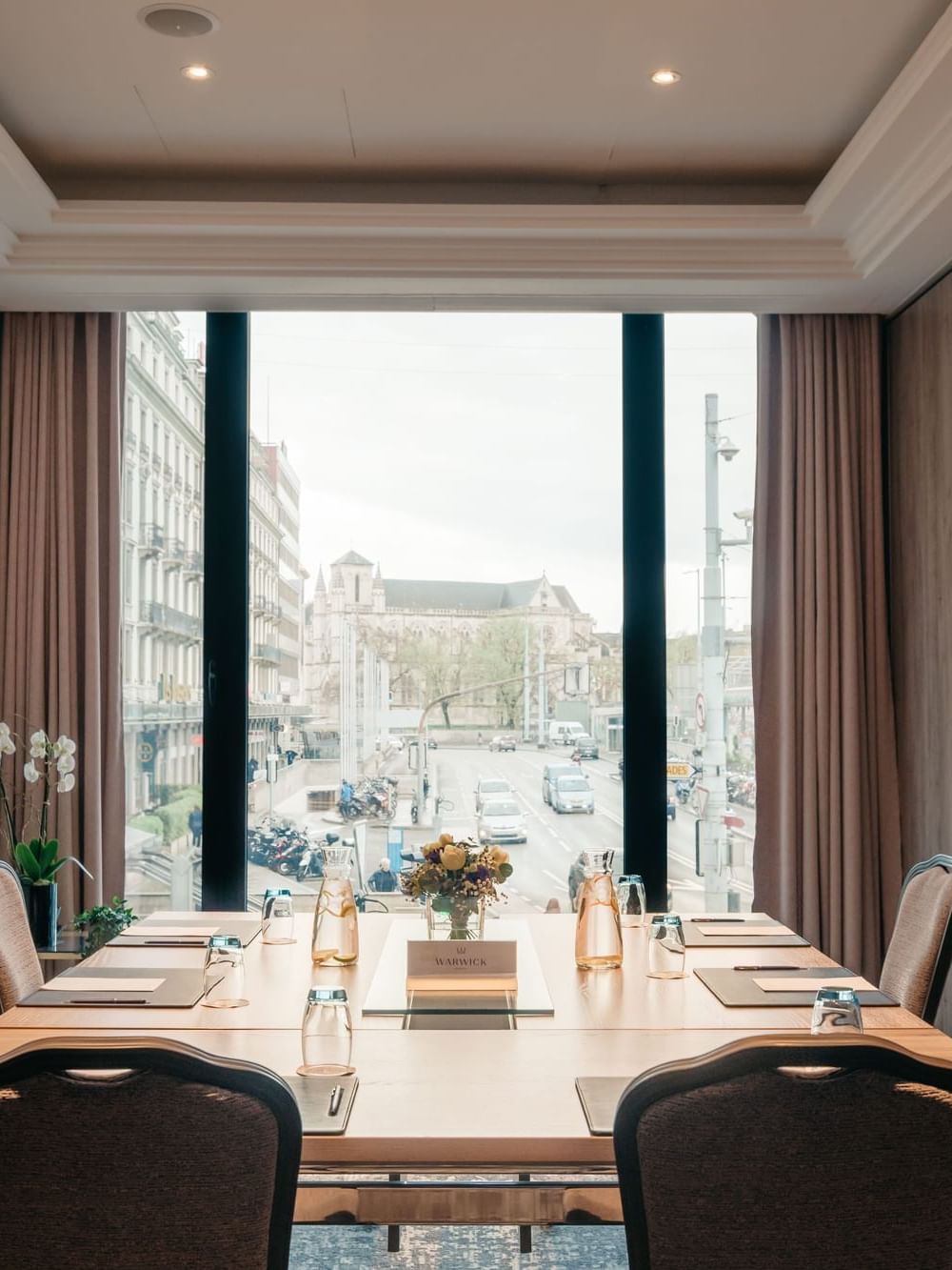 Square meeting table by chairs under a tray ceiling near a tall window in Cervin at Warwick Geneva