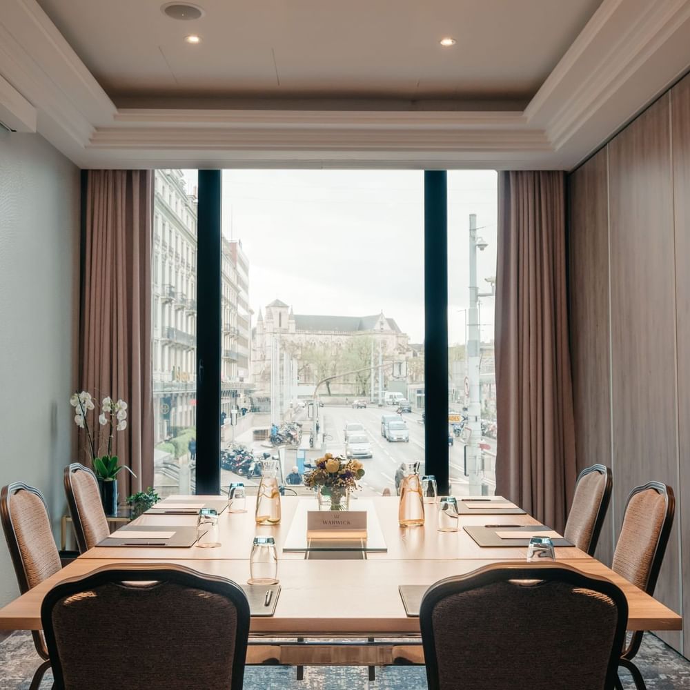 Square meeting table by chairs under a tray ceiling near a tall window in Cervin at Warwick Geneva