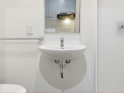 Clean white bathroom with wall-mounted sink and towel bar at Student Living Auckland - Beach.