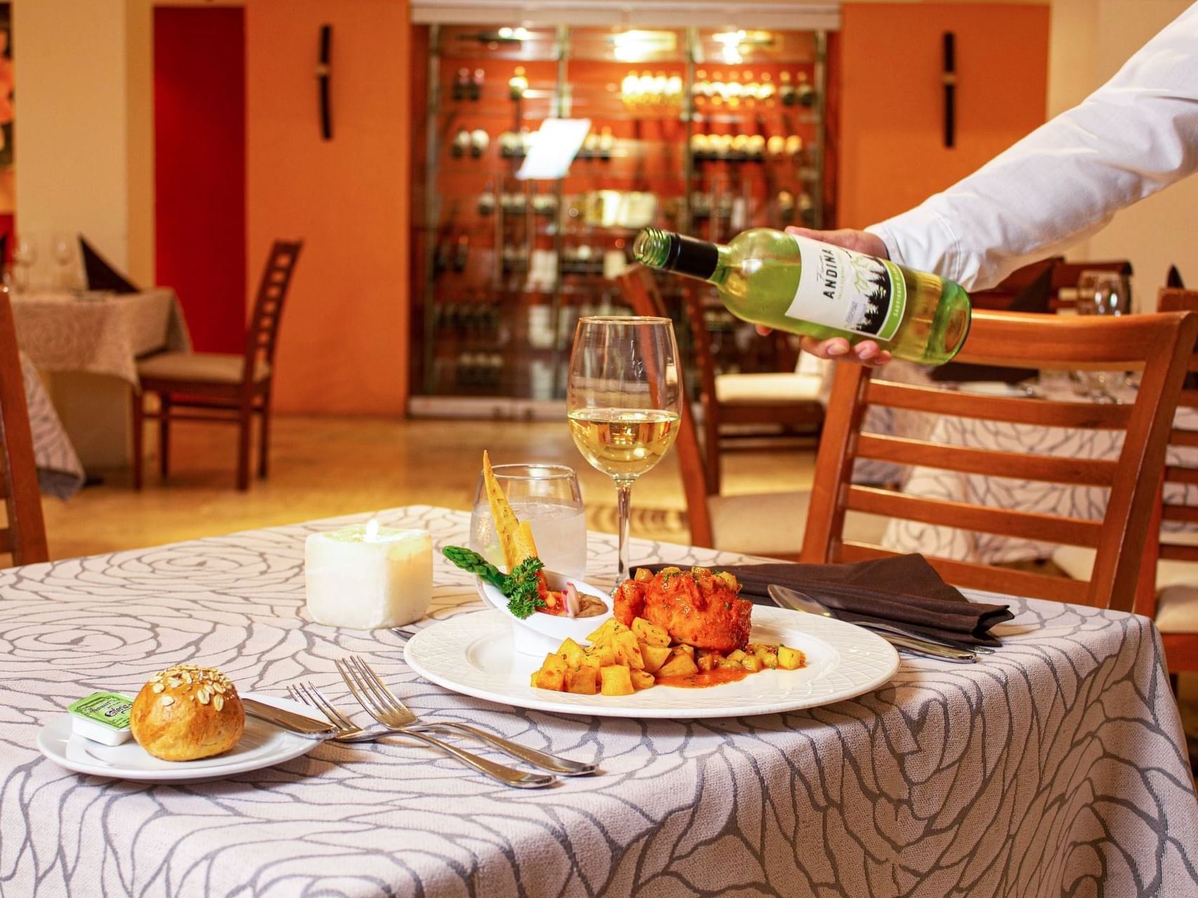 Bartender pouring wine into a glass in La Flor De Calabaza Restaurant at Plaza Pelicanos Grand Beach Resort