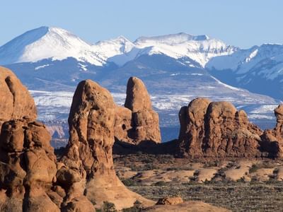 Snow-capped mountains overlook towering red rock formations in Arches National Park near Moab Valley Inn