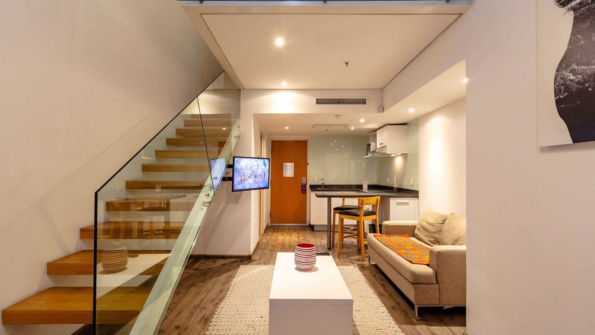 Queen Loft Bed at Camino Real Puebla Angelopolis showing a wooden staircase, small kitchen, and living area