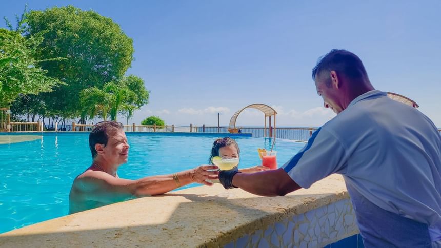 A couple having cocktails while enjoying the pool at Hotel Isla Del Encanto
