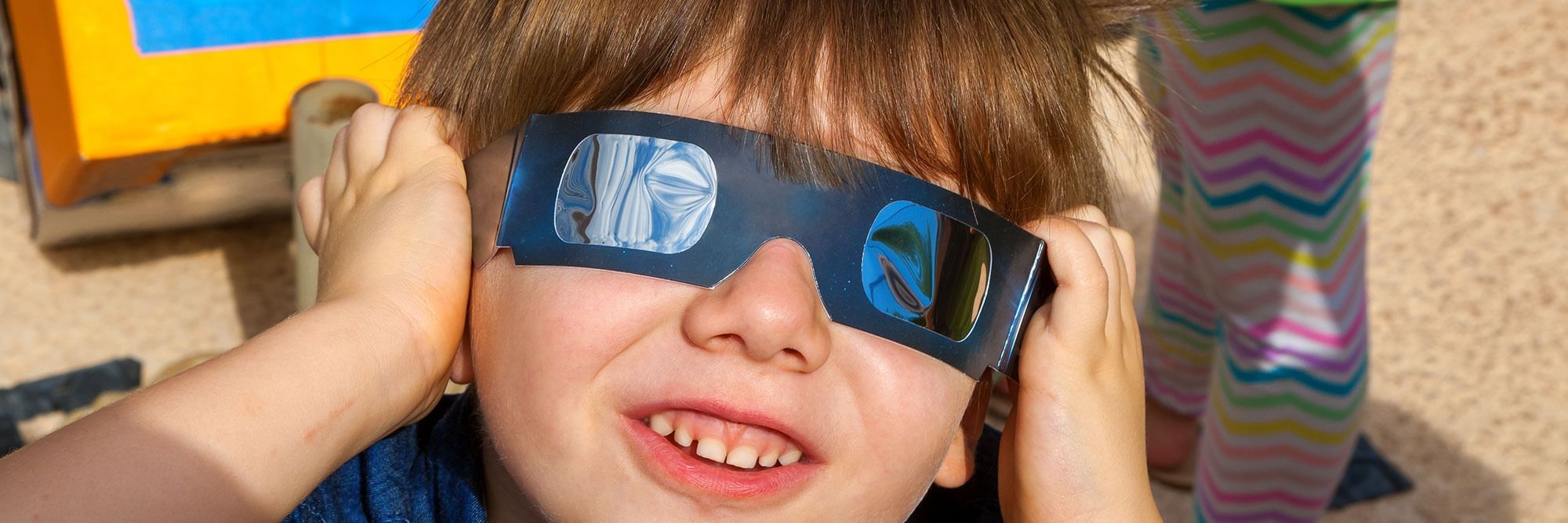 Child wearing solar eclipse glasses.