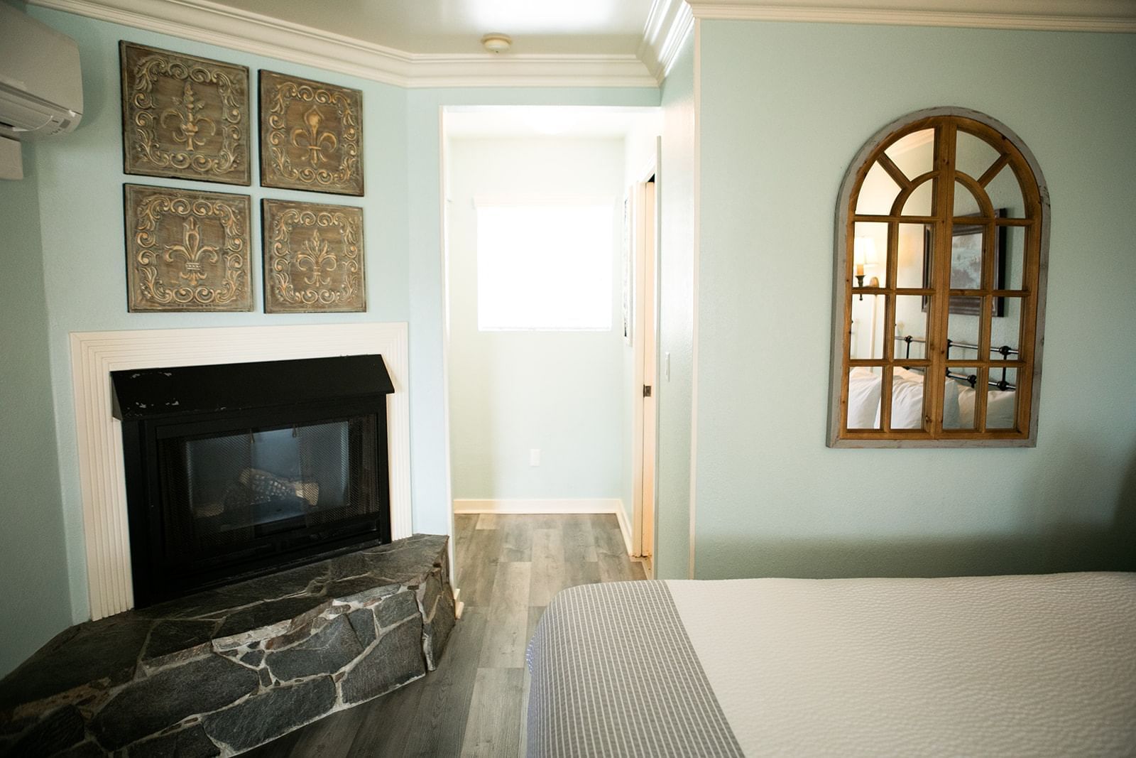 A room with a fireplace, bed, and mirror