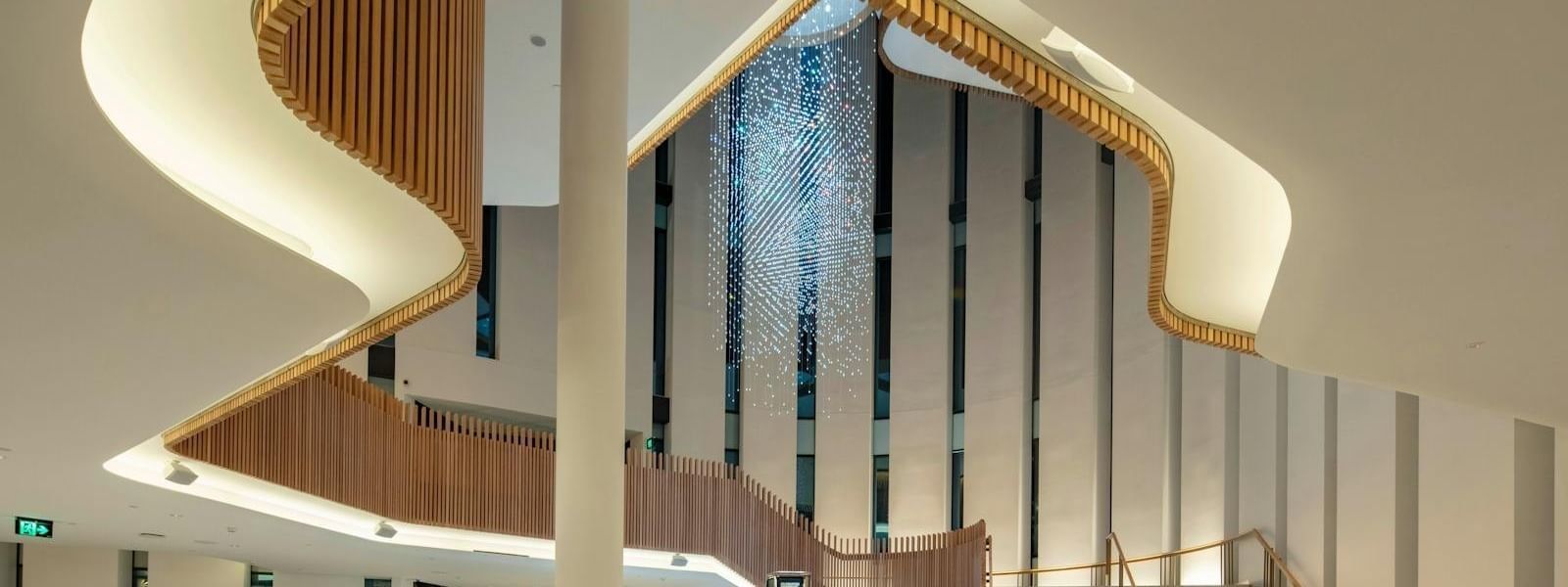 Interior of a modern architectural building with a spiral staircase and a decorative light installation.