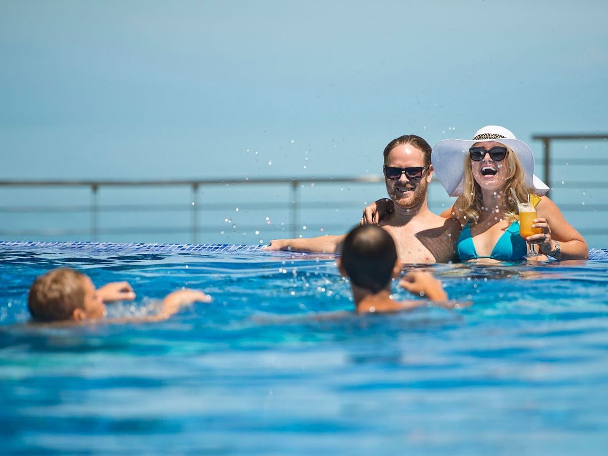 A family splashing in the outdoor pool of Los Altos Resort