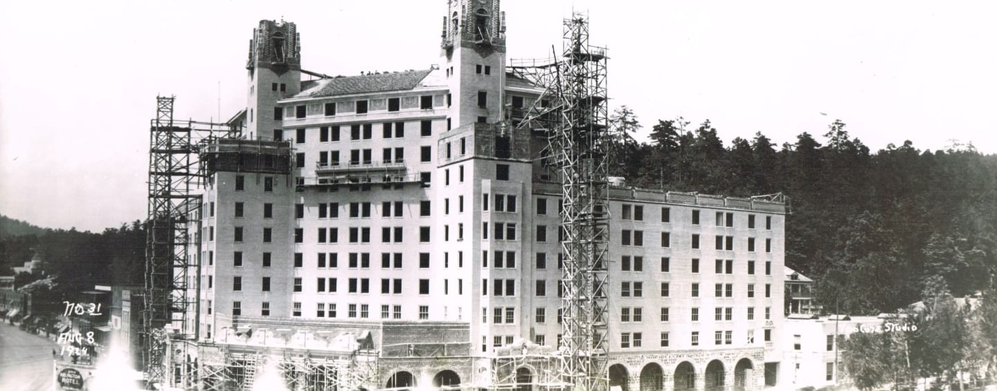 Scaffolding by twin towers under a clear sky surrounding the rising stone facade of Arlington Resort Hotel & Spa