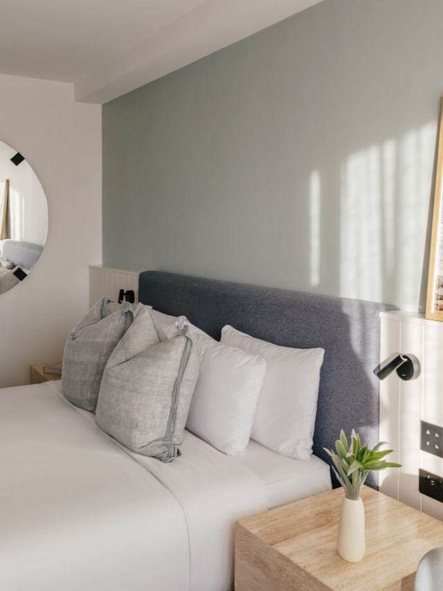 Sunset View King at Elysium Manly with linen pillows by a round mirror & a wooden nightstand, best places to stay in Manly