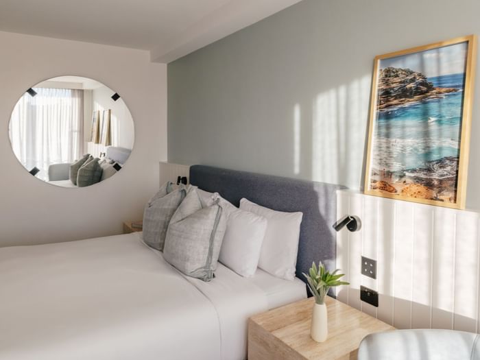 Sunset View King at Elysium Manly with linen pillows by a round mirror & a wooden nightstand, best places to stay in Manly