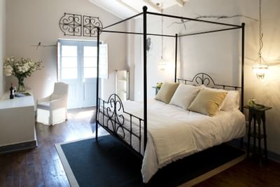 Four-poster bed on a rug by a white armchair under a vaulted ceiling in a room at NOI Blend Colchagua