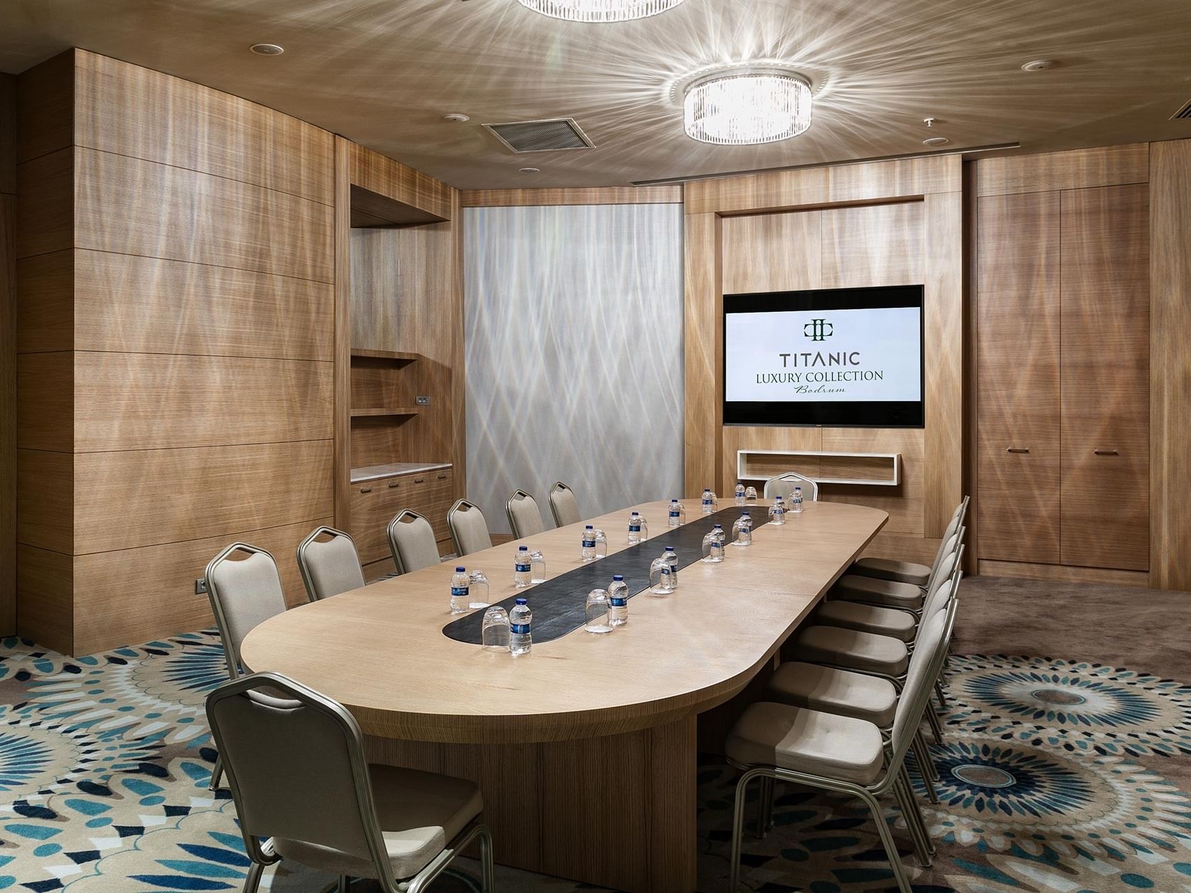 A stylish meeting room with a large table and screen at Titanic Luxury Collection Bodrum.