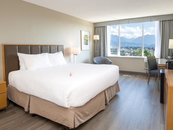 A hotel room with a king bed, large window, and pond view.
