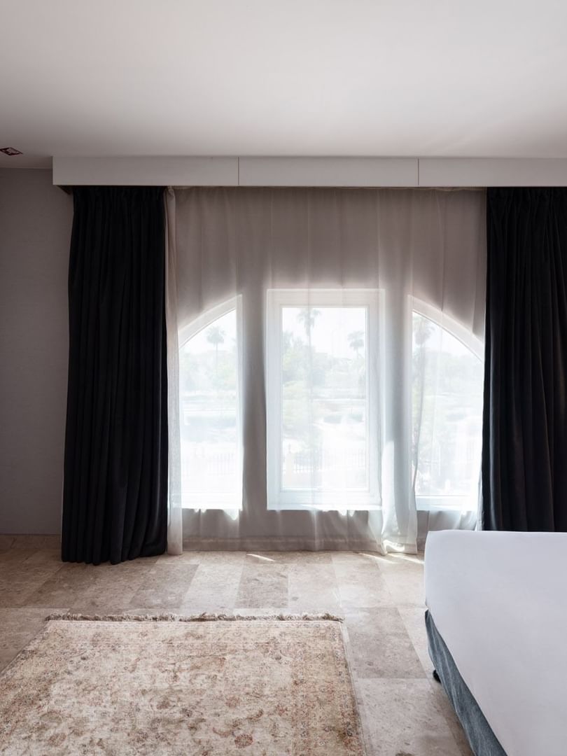 Junior Suite City View features a bed under black curtains, near a console with a TV at Warwick Al Jubail