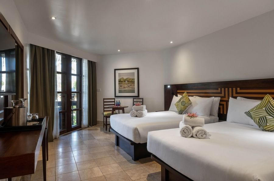 White twin beds with towels by a small table under framed in Double Double Ocean View at Warwick Fiji Resort and Spa