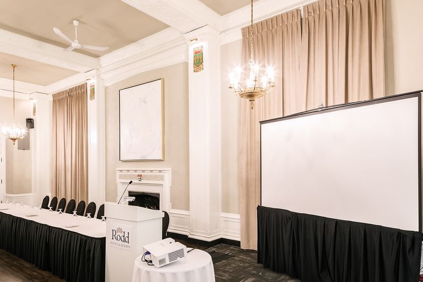 White podium by a projector screen under a classic brass chandelier in a meeting room at Rodd Charlottetown Hotel
