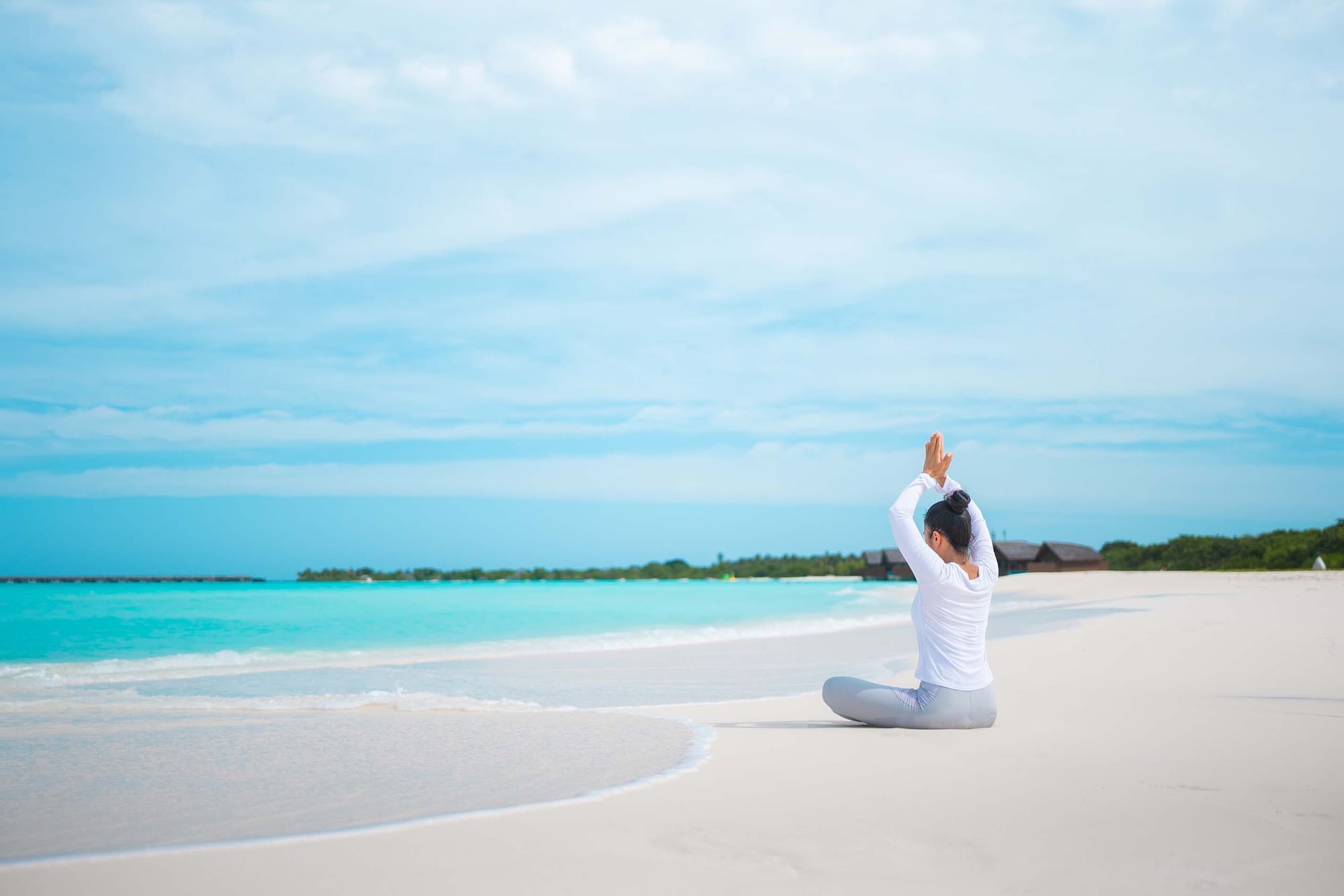 A woman engaged in yoga on the beach, The Signature Collection