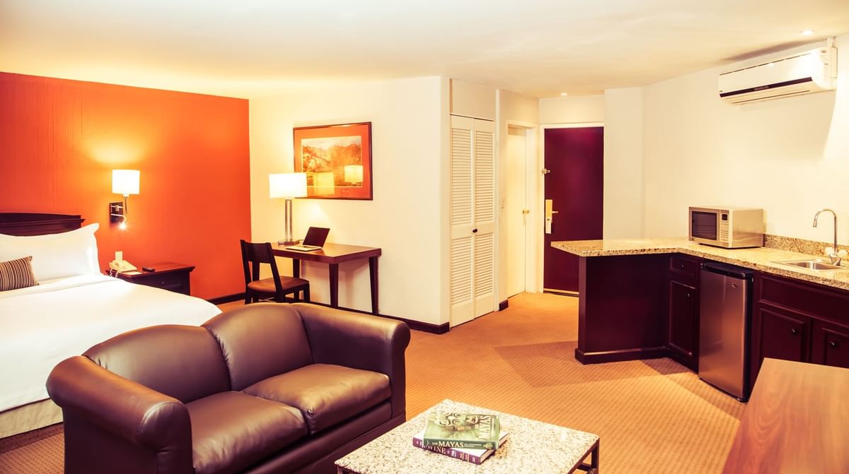 Interior de la suite junior con sala de estar y cocina pequeña en Gamma Hotels