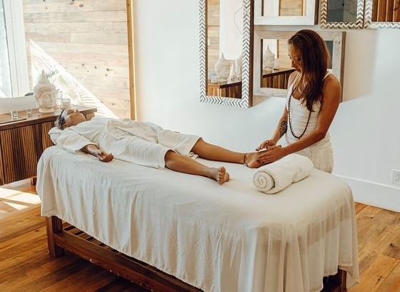 A guest enjoys a relaxing foot massage on a table inside a tranquil spa room at the Ibagari Hotel