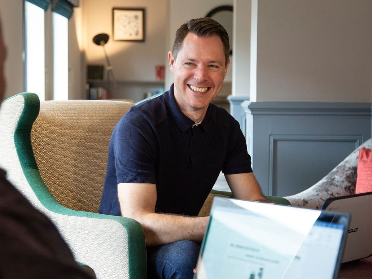 A man working with a laptop smiling at Bridgewood Manor Hotel