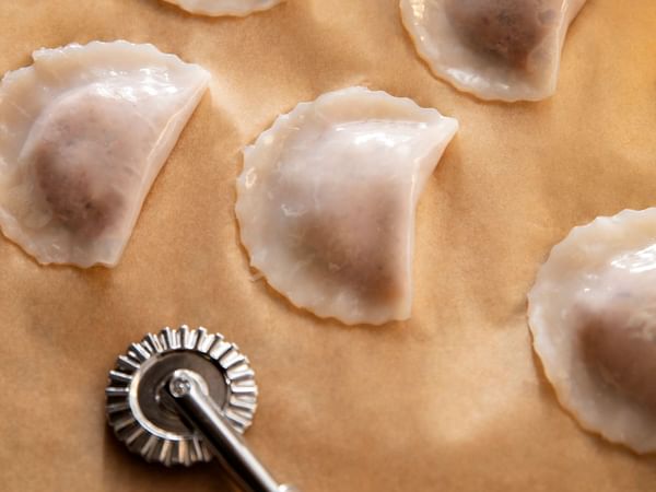 Dumplings on parchment paper with crimping tool, highlighting the pleats and fillings of each dumpling.