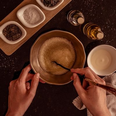 Mixing ingredients in a bowl beside spices, salt, and oil on a dark counter at Falkensteiner Hotel Bratislava