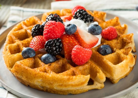 Close-up of waffles topped with whipped cream & berries served at Gorges Grant Hotel
