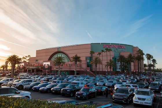 The Honda Center by a crowded parking lot under a sunset sky near Anaheim Portofino Inn & Suites