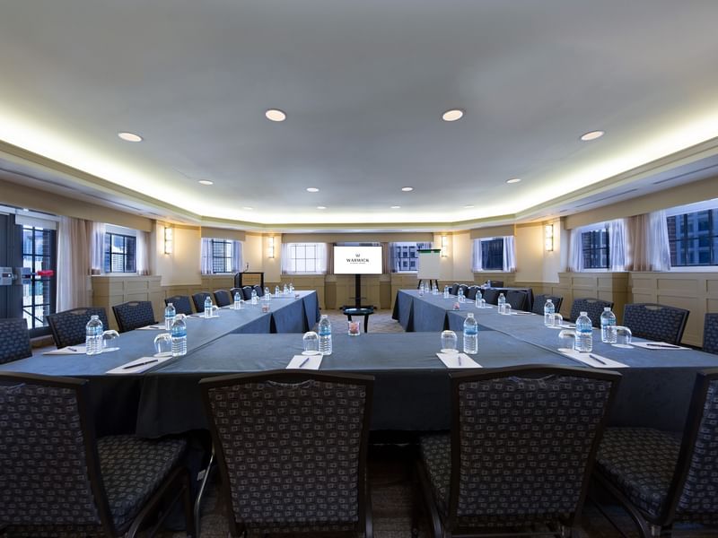 U-shaped table setup with chairs facing the projector screen in Michigan Room at Warwick Allerton Chicago
