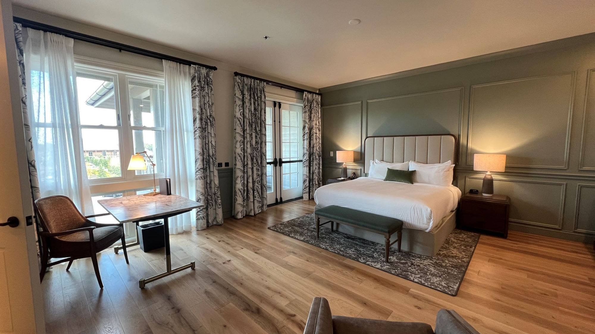 Work desk & lounge area with wooden floors by the bed in King Room With Balcony at Camp Creek Inn