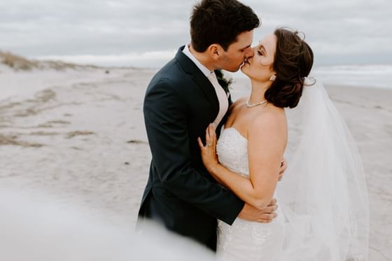 Newlywed couple kiss on the beach at our Avalon wedding venue
