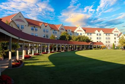 Branson Hillside Hotel exterior with a red roof, curved walkway, and a lush green lawn under a blue sky