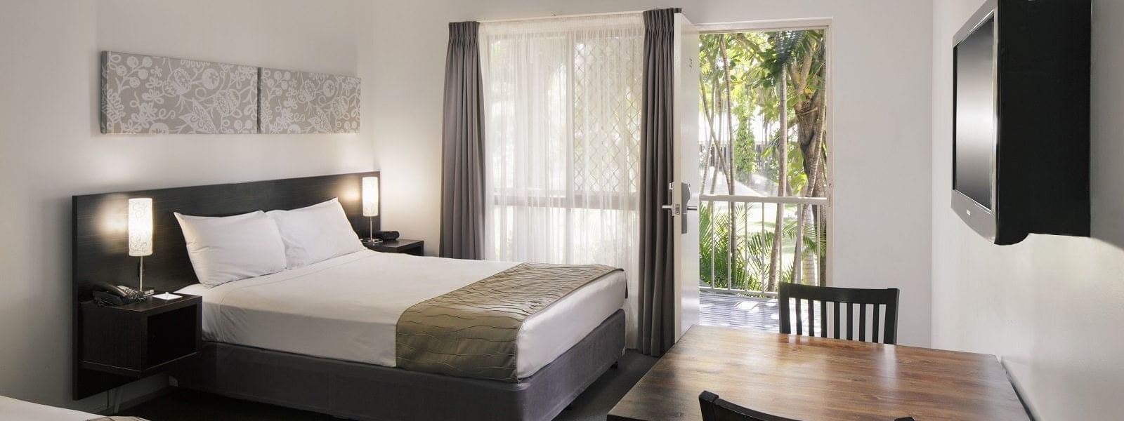 Standard Twin room featuring a queen bed, dining table, and large window with garden views at Mercure Hotel Townsville