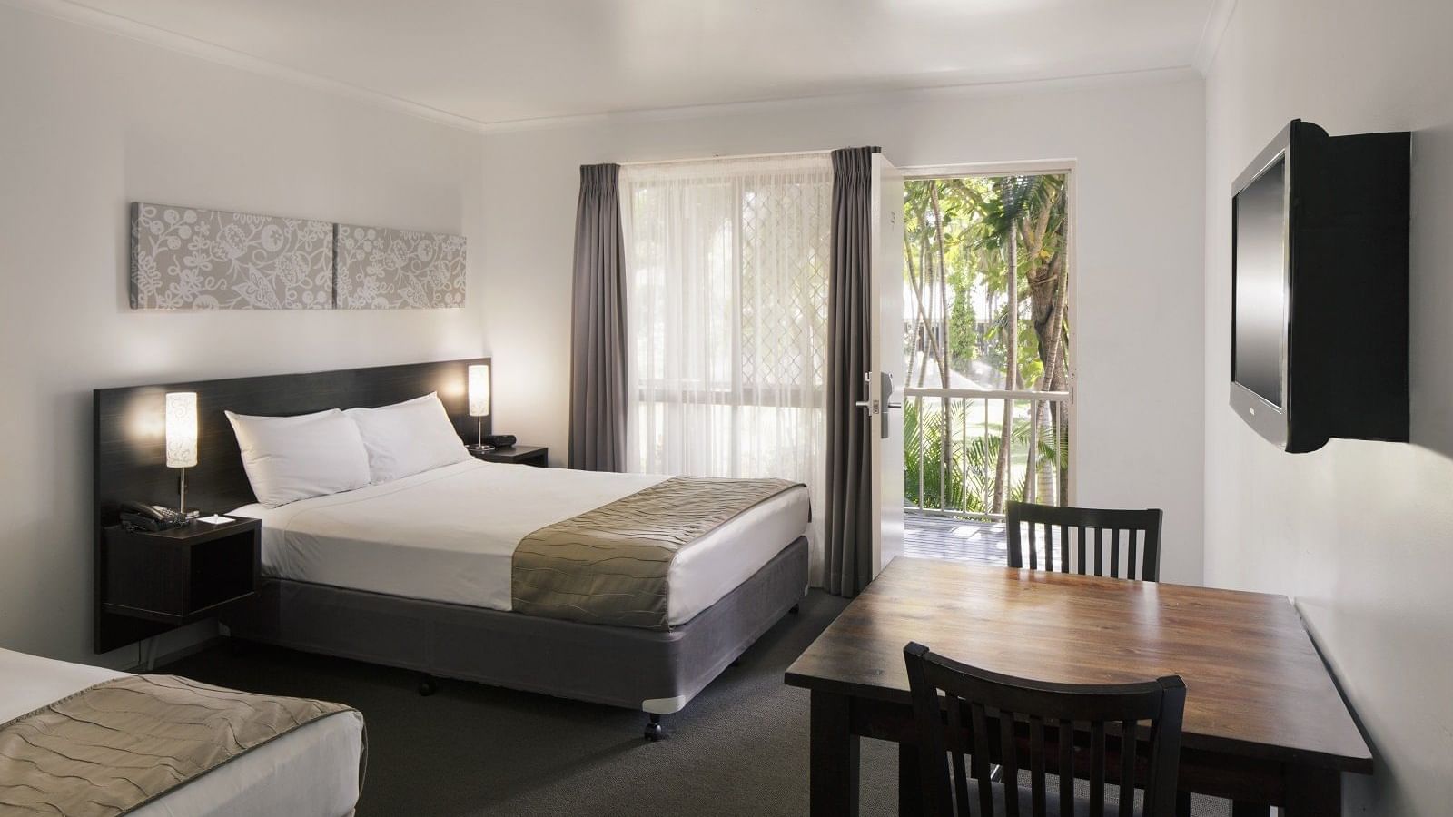 Standard Twin room featuring a queen bed, dining table, and large window with garden views at Mercure Hotel Townsville