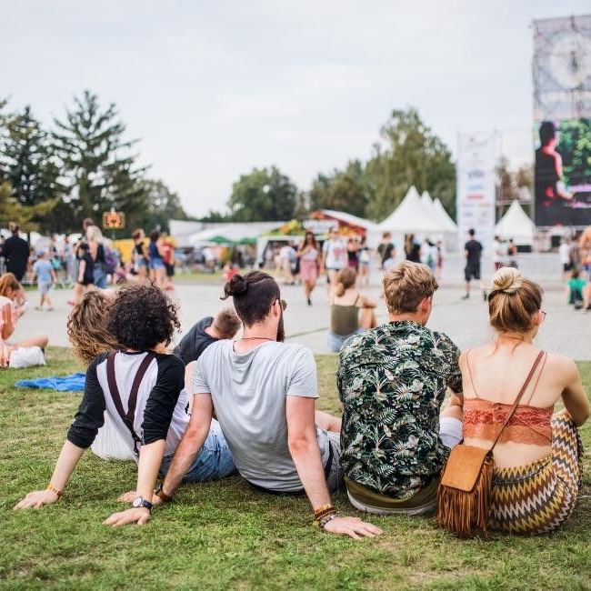 Festival goers sitting on grass with stage in background for Reading Festival: All You Need To Know!