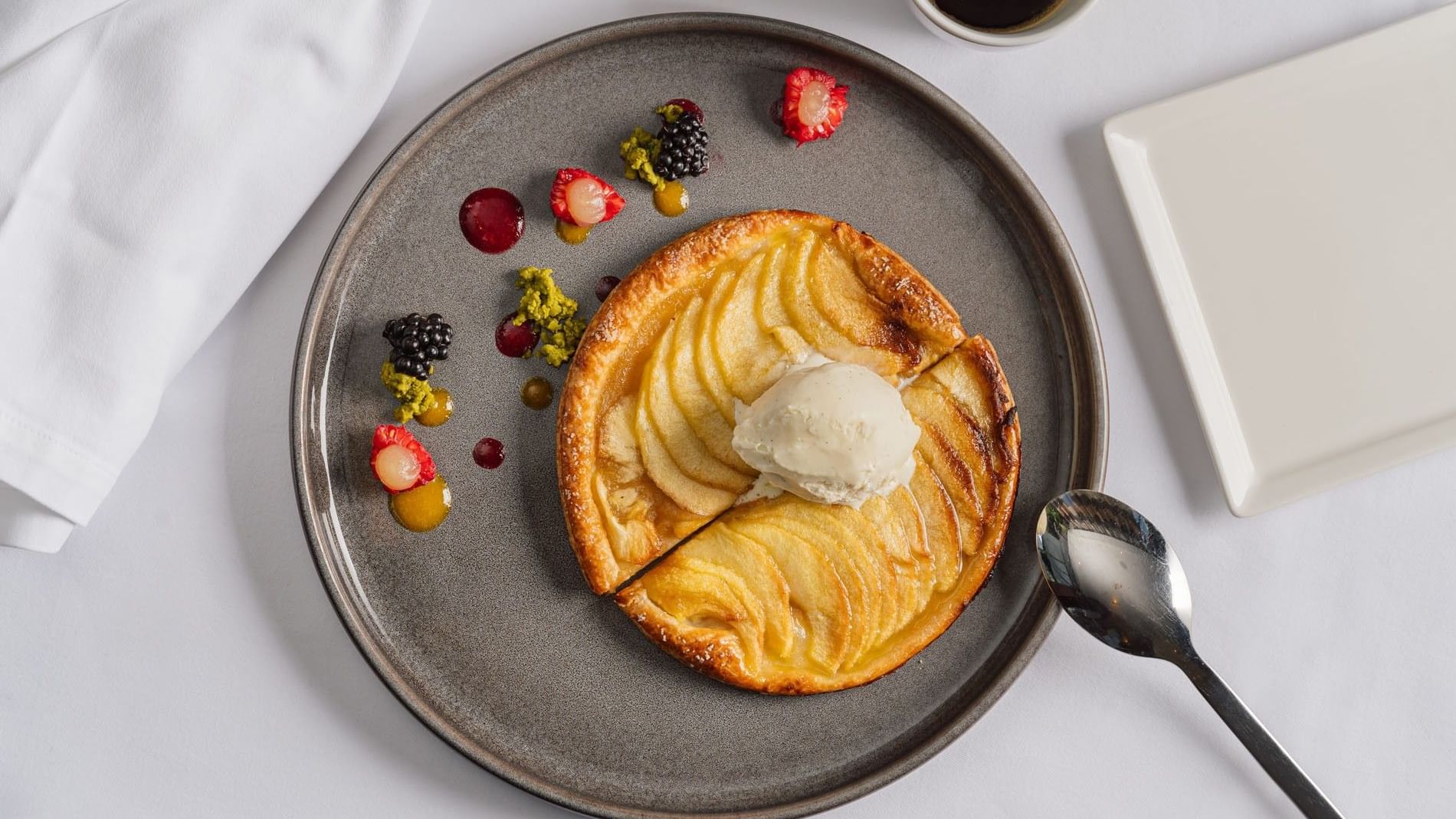 Gourmet apple tart with ice cream and fresh berries under soft light in Sunday Brunch at Warwick Geneva