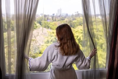 A guest pulls back the curtains to admire the beautiful parkland view from the Royal on the Park Hotel