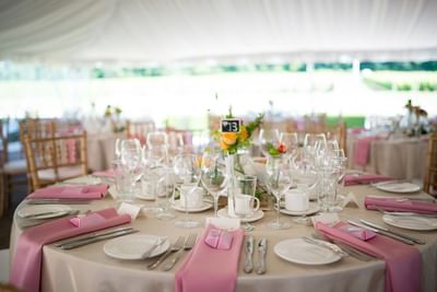 Table setup with pink napkins and glassware inside Spencer Meadows Pavilion at Spencer Hotel & Conference Centre