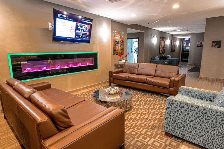 Interior view of the lobby area with cozy sofa and a TV at Encore Suites Grande Prairie