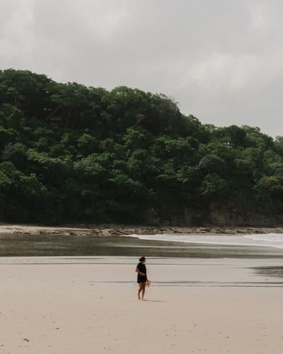 Una mujer caminando por la tranquila playa privada de arena en Morgan's Rock Reserve & Ecolodge, Nicaragua.