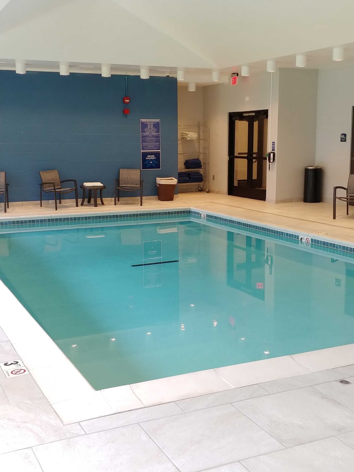 Clean indoor swimming pool with blue tiled edges and lounge chairs against the wall at Shangri-La Resort and Golf Club
