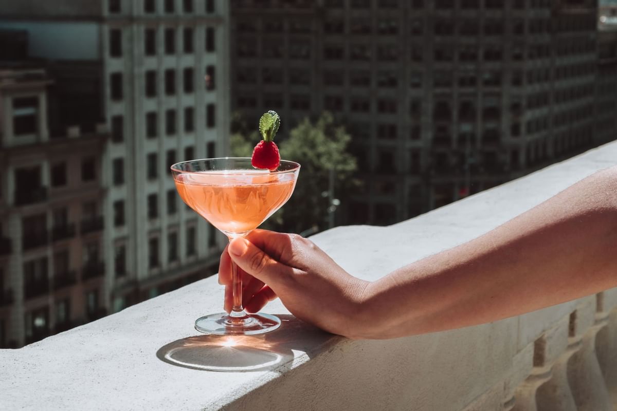 A cocktail & balcony view on a sunny day at Almanac Barcelona rooftop bar