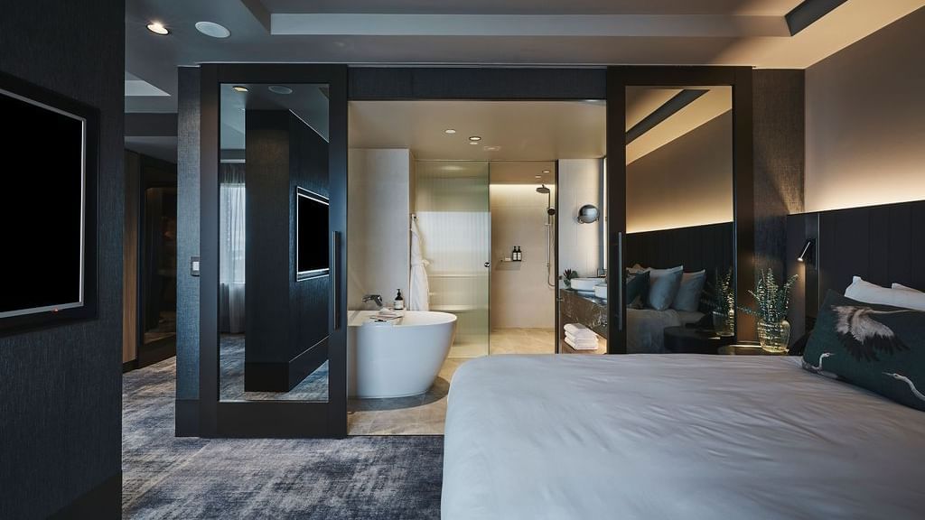 Superior Suite with king bed, freestanding bathtub, and modern dark wood finishes at Pullman East Melbourne
